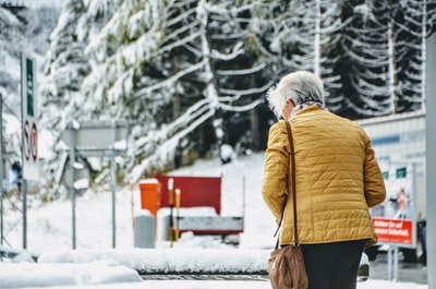 女人穿着棕色夹克和黑色绗缝在雪地行走的底部
